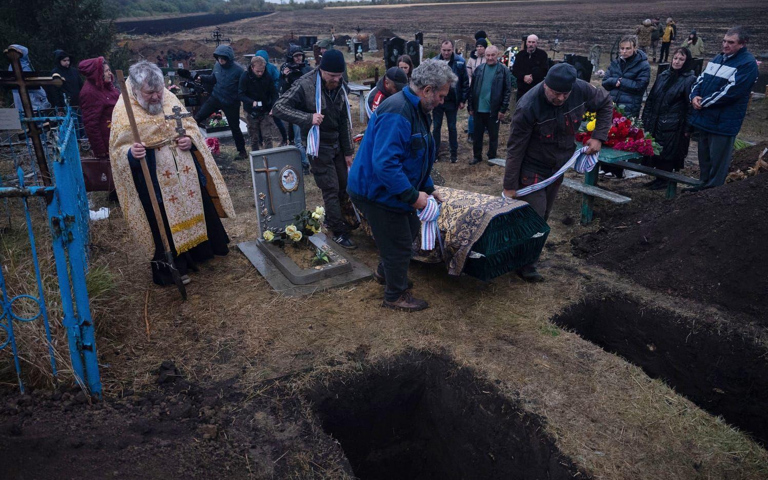 Men carry a coffin for burial during a funeral ceremony for Tetiana Androsovych, 60, and Mykola Androsovych, 63, killed by a rocket strike, at a graveyard in the village of Hroza, near Kharkiv, Ukraine, Saturday, Oct. 7, 2023. The Ukrainian village of Hroza has been plunged into mourning by a Russian rocket strike on a village store and cafe that killed more than 50 people on Thursday, Oct. 5. (AP Photo/Alex Babenko)  XBP111